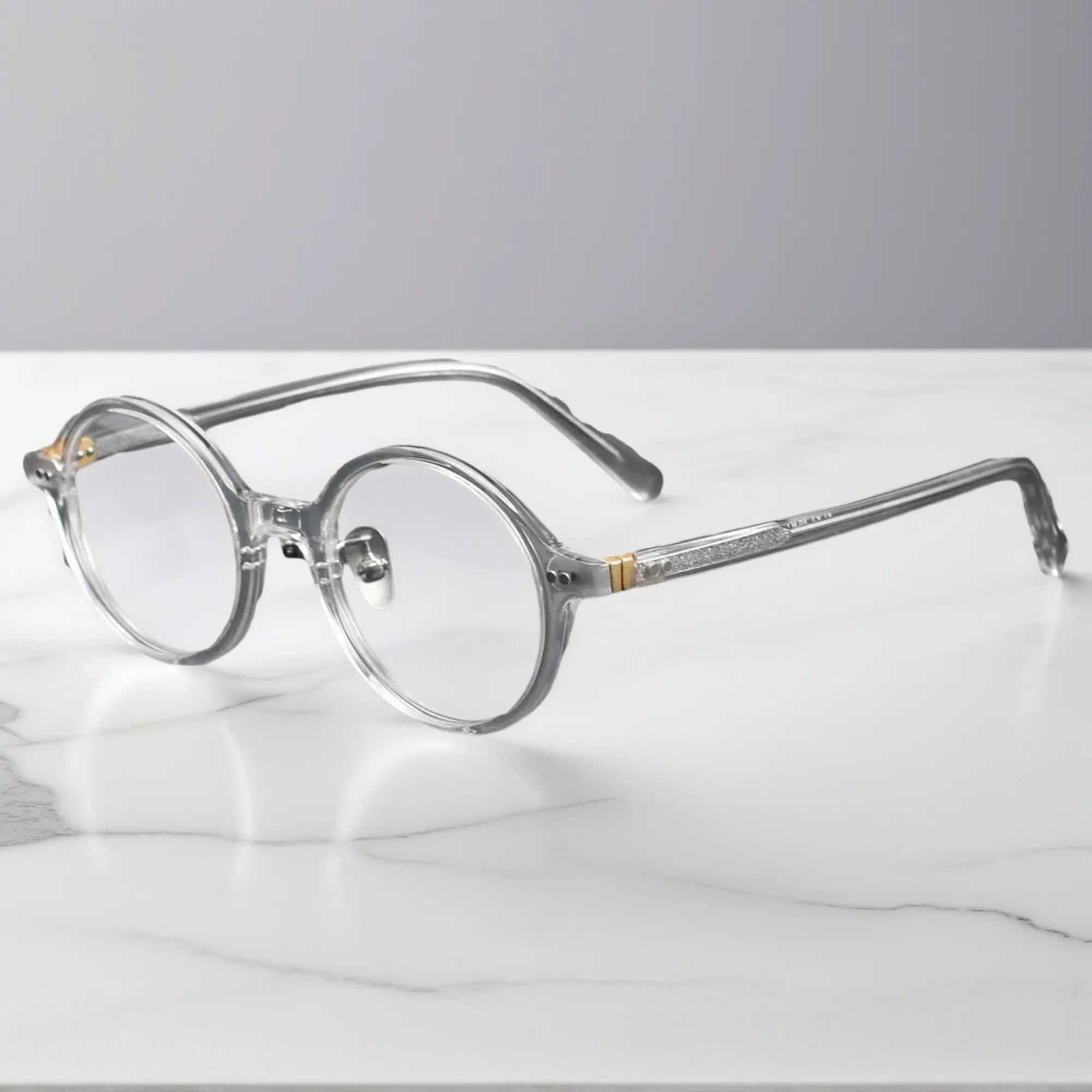 Clear round eyeglasses showing titanium nose pads and metal-insert hinges